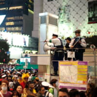 Police officials try to subdue massive crowds at a crossing near Shibuya Station on Thursday night amid the chaos of the annual Halloween celebrations. | RYUSEI TAKAHASHI