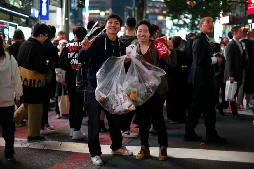 Yuki Satake (left) and Masaki Takuma pick up trash in Shibuya during Halloween festivities on Thursday night. | RYUSEI TAKAHASHI