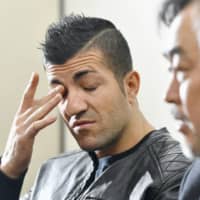 A Kurdish man, who has sued Japan\'s government for leaving him untreated for cancer during his detention in Ibaraki Prefecture, wipes his eye during a news conference in Tokyo on Tuesday. | KYODO