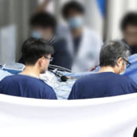 Shinji Aoba, the suspect in a deadly arson attack on a Kyoto Animation Co. studio in July, is carried on a stretcher to a Kyoto hospital Thursday from one in Osaka Prefecture after undergoing multiple skin grafts. | KYODO