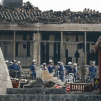 Firefighters continue their investigation Saturday in the burned-down Seiden main hall of Shuri Castle in Naha, Okinawa Prefecture, which was destroyed by fire last week. | KYODO