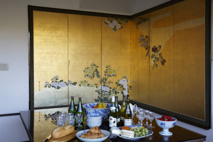 Gallery wall: Private concerts at the Takishita residence are followed by buffet-style refreshments. A friend gave Takishita the idea of utilizing this six-panel byōbu from the Edo Period— which can form a perfect right angle when folded in the middle — for corner arrangements like this one.