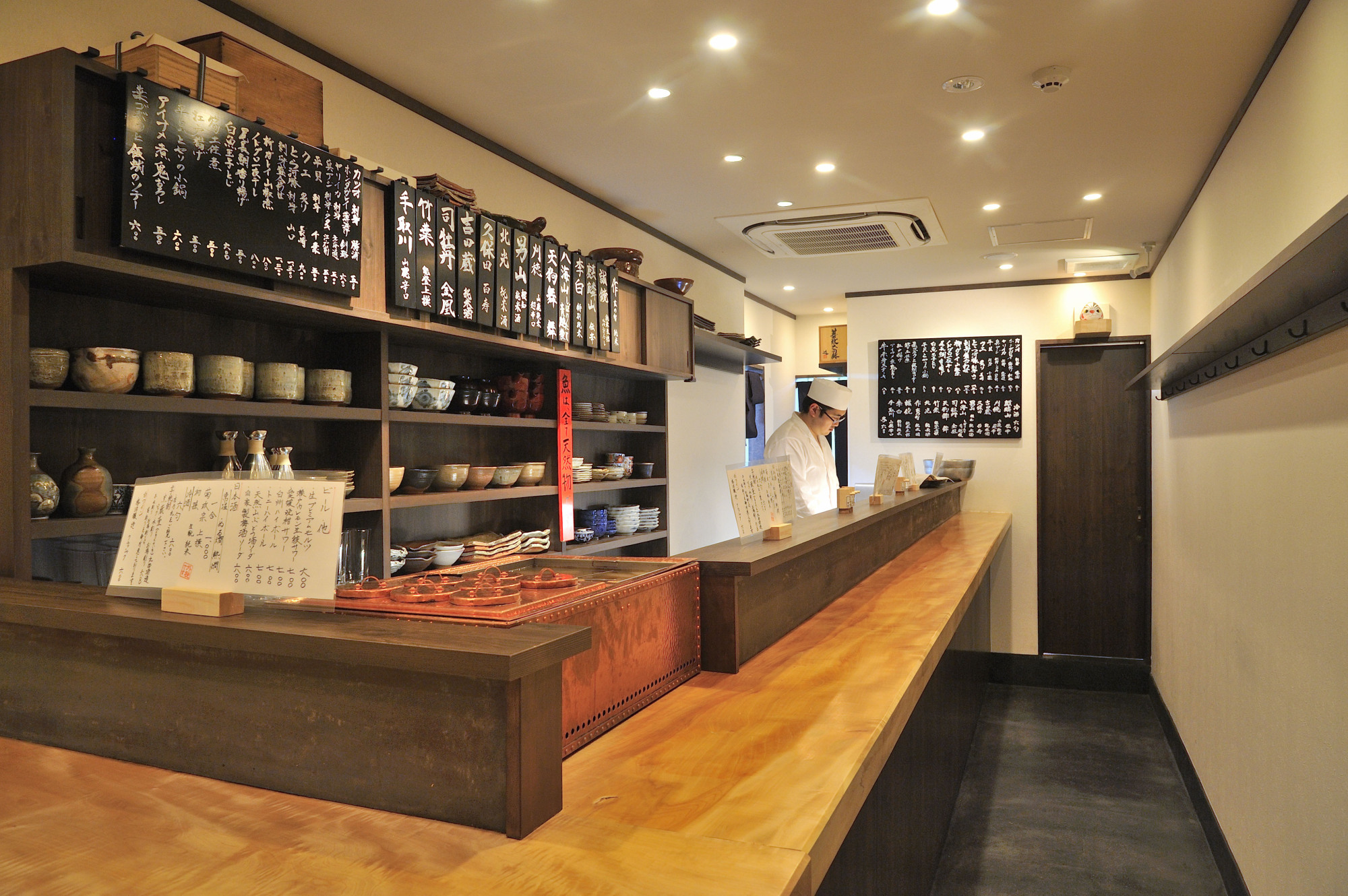 A tipple or two: One end of Sunbun's L-shaped counter is dominated by a kandōko (water bath for warming sake). | COURTESY OF SANBUN