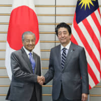 Malaysian Prime Minister Tun Dr. Mahathir Mohamad and Japanese Prime Minister Shinzo Abe shake hands during their meeting in Tokyo on May 31. Mahathir has adopted the Look East Policy modeled after Japan\'s economic growth since his first term as prime minister between 1981 and 2003. | CABINET PUBLIC RELATIONS OFFICE