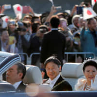 Emperor Naruhito and Empress Masako wave to well-wishers watching the Nov. 10 enthronement parade. | REUTERS