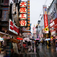 People stroll through a shopping district in Osaka on Thursday.  The government\'s challenge will be to put together a spending package that shores up consumer spending and increases the economy\'s growth potential. | REUTERS
