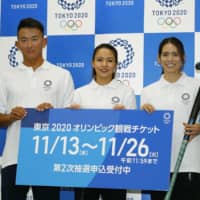 Hockey players Maho Segawa (center) and Maki Naito (right), joined by beach volleyball player Takumi Takahashi, pose at a news conference promoting the second Olympic ticket lottery for residents of Japan on Wednesday in Tokyo. | KYODO