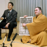 Wakanoho (right) points out his name on the banzuke ranking for the 2007 Kyushu Basho, after winning promotion to the makuuchi division, on Oct. 29, 2007, in Kitakyushu. | KYODO