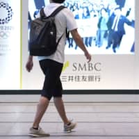 A Sumitomo Mitsui Banking Corp. employee walks towards the company\'s head office in Tokyo on Monday. | BLOOMBERG