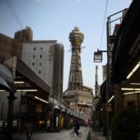 Tsutenkaku Tower rises above the Shinsekai shopping district in Osaka. | BLOOMBERG