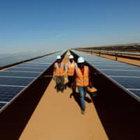 Workers walk between photovoltaic panels at the Benban plant in Aswan, Egypt, in November. | REUTERS