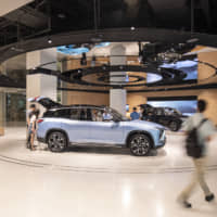 Shoppers look at a NIO ES8 sports utility vehicle at the NIO House in Shanghai Tower. | BLOOMBERG