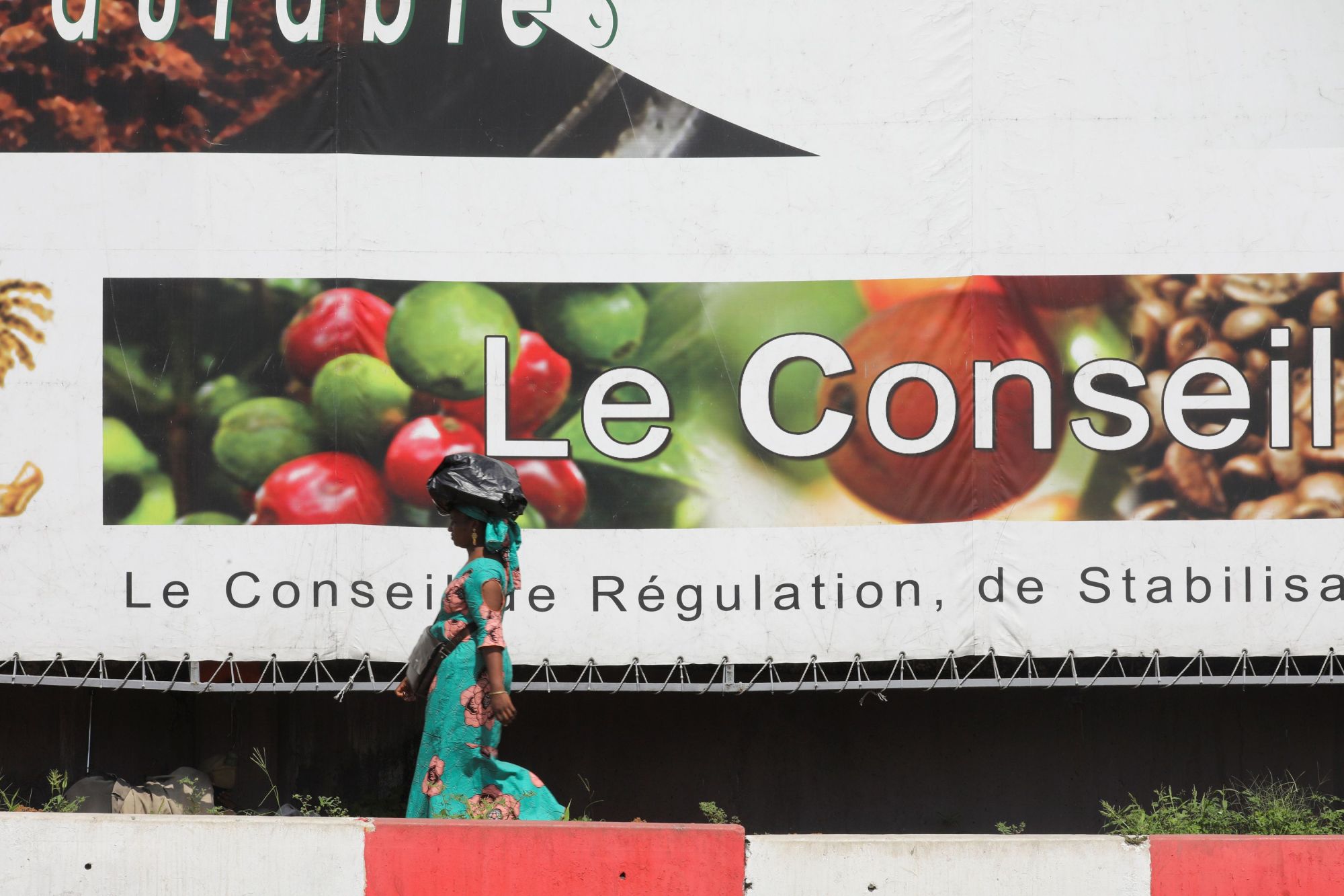 A woman passes near a big barnner of the Coffee-Cocoa Council (CCC), in a street in Abidjan Dec. 9. | REUTERS
