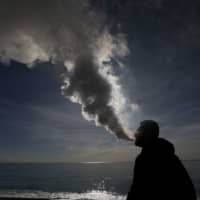 A man vapes on the beach in Nice, France, in January. | REUTERS