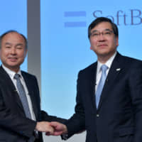 SoftBank Group CEO Masayoshi Son (left) and Makoto Gonokami, president of the University of Tokyo, shake hands during a news conference at the University of Tokyo. | YOSHIAKI MIURA
