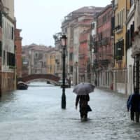 People walk in a flooded street during a period of seasonal high water in Venice, Italy, in 2012. | REUTERS
