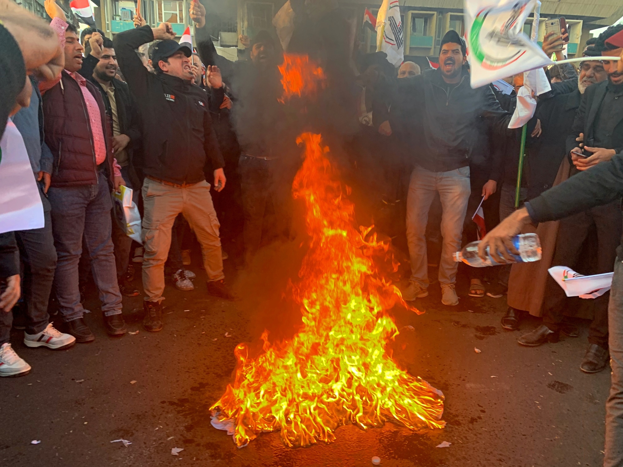 Protesters burn a representation of a U.S. flag during a rally against the U.S. strikes on the Hezbollah Brigades militia, in Tahrir Square, Baghdad, Monday. The Iranian-backed militia said Monday that the death toll from U.S. military strikes in Iraq and Syria against its fighters has risen to 25. | AP