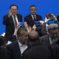 Shohrat Zakir, chairman of China\'s Xinjiang Uighur Autonomous Region, left reacts to journalists as he leaves after a news conference in Beijing on Monday. | AP