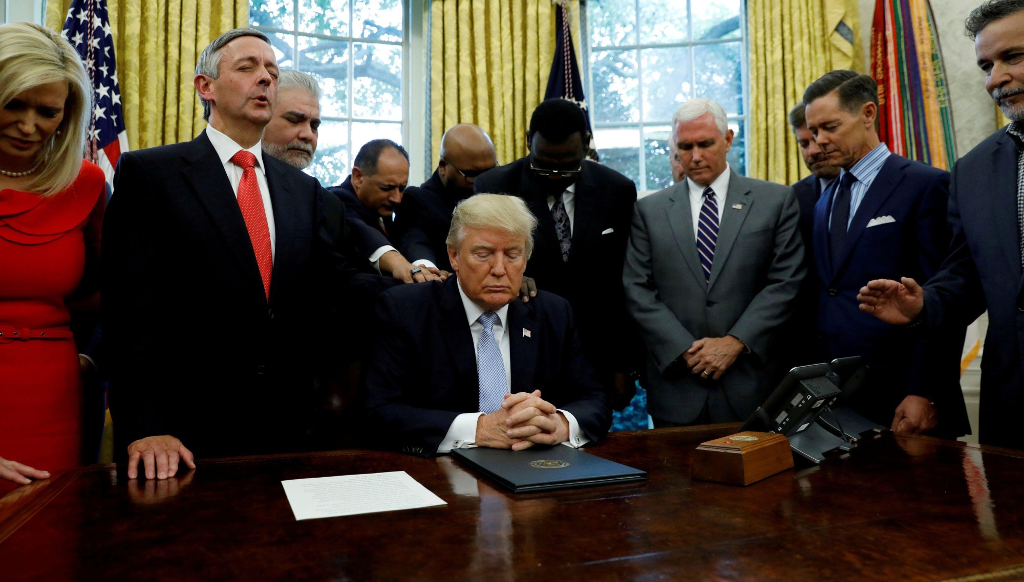 Faith leaders place their hands on the shoulders of U.S. President Donald Trump as he takes part in a prayer for those affected by Hurricane Harvey in the Oval Office of the White House in Washington in 2017. | REUTERS