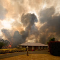 A bushfire burns behind a property in Balmoral, 150 km southwest of Sydney, on Thursday. | AFP-JIJI