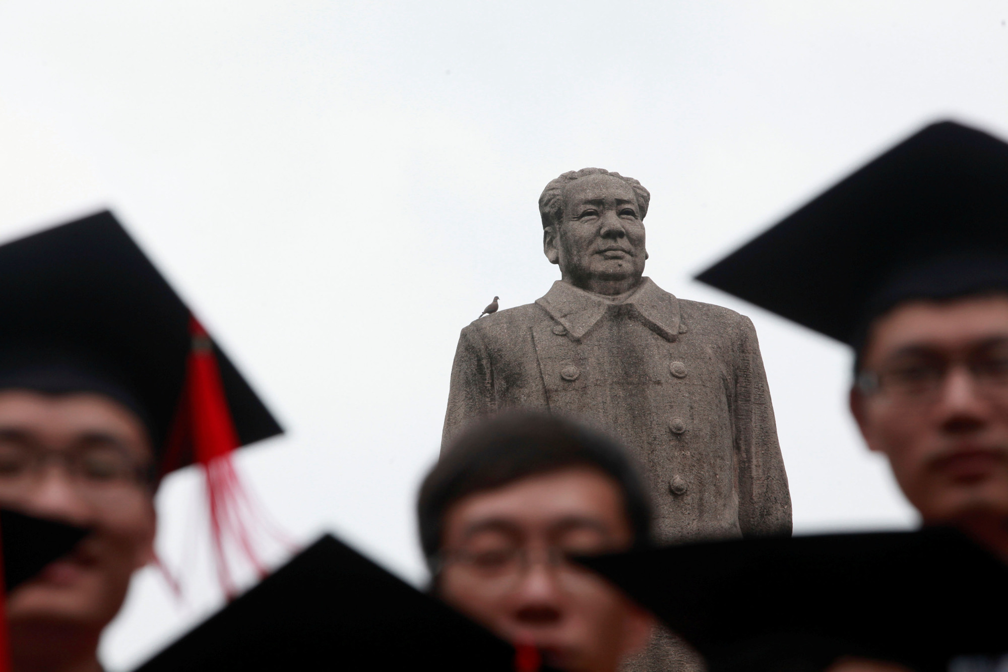 A statue of the late Chinese leader Mao Zedong overlooks a graduation ceremony at Fudan University in Shanghai. | REUTERS