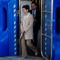 Hong Kong Chief Executive Carrie Lam walks out from a gate to receive petition letters from protesters before her weekly news conference on Tuesday. | AFP-JIJI
