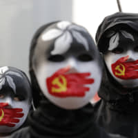 People wearing masks stand during a rally to show support for Uighurs and their fight for human rights in Hong Kong on Sunday. | AP
