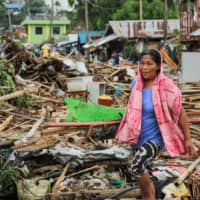 A resident walks past debris from destroyed houses after Typhoon Kammuri hit the city of Sorsogon, south of of Manila, on Tuesday. | AFP-JIJI