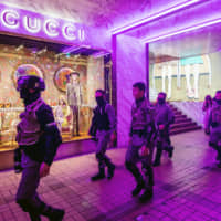 Riot police walk past a Guccio Gucci SpA store in the Tsim Sha Tsui district of Hong Kong on Sunday. | BLOOMBERG