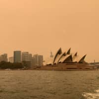Haze from wildfires obscures the sun setting above the Sydney Opera House on Dec. 6. | REUTERS