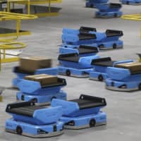 Amazon and its rivals are increasingly requiring warehouse employees to get used to working with robots. The company now has more than 200,000 robotic vehicles it calls \"drives\" that are moving goods through its delivery-fulfillment centers around the U.S. | AP