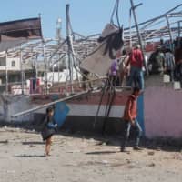 People gather at the scene of a blast that struck a military graduation parade in the town of al-Dhalea, Yemen, Sunday. | REUTERS