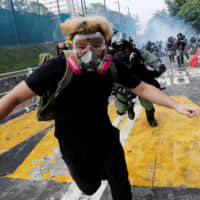 A protester flees from riot police at the Chinese University of Hong Kong on Nov. 12. | REUTERS