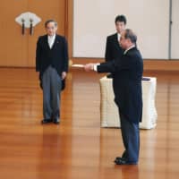 Yasuhiko Nishimura (right) receives an attestation from Emperor Naruhito for his new position as the head of the Imperial Household Agency at the Imperial Palace in Tokyo on Tuesday. | POOL / VIA KYODO