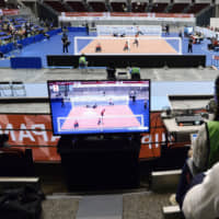 Spectators don headphones so they can listen to the on-court comments of players and view the action on an arena screen. | KYODO