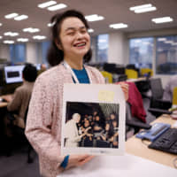 Reuters employee Mayuko Baba displays her commemorative photo of Pope John Paul II with her at the Vatican, taken in 1989 during her trip as a Sophia University student, at her office in Tokyo on Nov. 22. | REUTERS