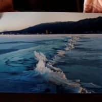 Shinto priest Kiyoshi Miyasaka displays a photo he took on Jan. 13, 2006, that shows a phenomenon called omiwatari (the crossing of the gods), which occurs when Lake Suwa freezes over and two sheets of ice collide to create a ridge across the surface. | REUTERS