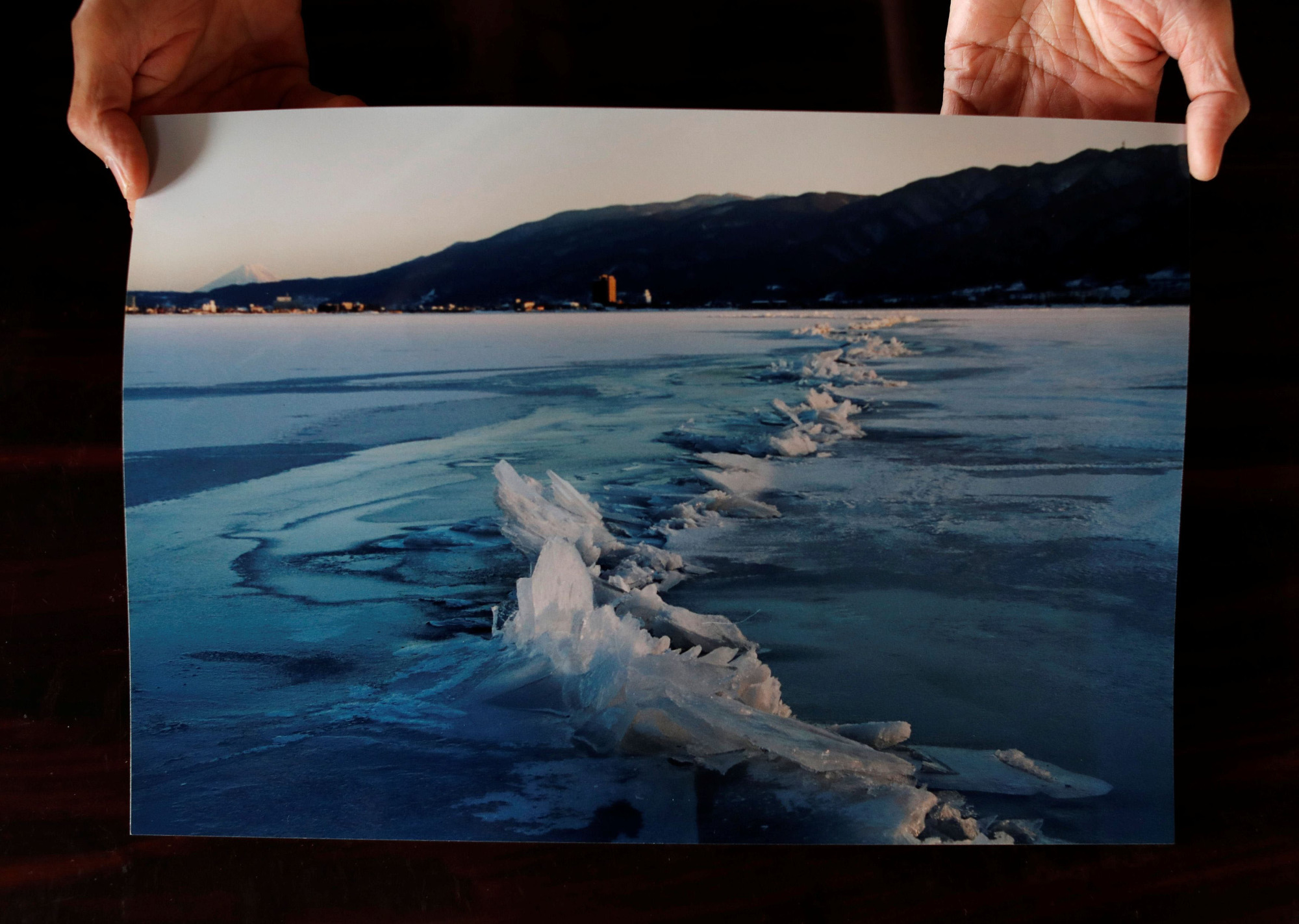 Shinto priest Kiyoshi Miyasaka displays a photo he took on Jan. 13, 2006, that shows a phenomenon called omiwatari (the crossing of the gods), which occurs when Lake Suwa freezes over and two sheets of ice collide to create a ridge across the surface. | REUTERS