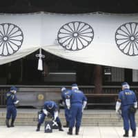 Police investigate in front of a worship hall at the war-linked Yasukuni Shrine in Tokyo on Aug. 19, after a Chinese man threw black ink on a curtain. | KYODO