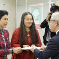 A couple receives a partnership certificate issued by the Yokohama Municipal Government on Monday as the city began recognizing the partnerships of sexual minorities and common-law couples. | KYODO