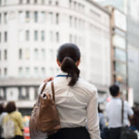 Looking forward: A woman stands in the commercial district of Ginza in Tokyo. | GETTY IMAGES