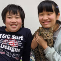 Best pals: Kentaro (left) and Yuna Shimaoka love their new cat, Latte, and Latte loves her new home. | KENJI SHIMAOKA