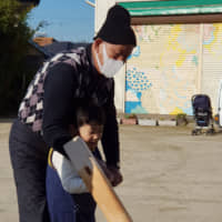 Passing down tradition: Tadashi Amano teaches his 7-year-old grandson, Minato, how to hold a mallet that is used to make rice cakes for the holidays. | AMY CHAVEZ