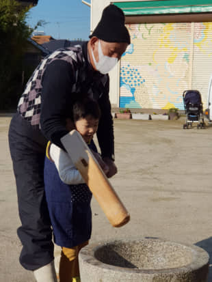 Passing down tradition: Tadashi Amano teaches his 7-year-old grandson, Minato, how to hold a mallet that is used to make rice cakes for the holidays. | AMY CHAVEZ