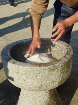 Think fast: The referee's hands fold a gooey lump of rice while it is hammered into a 'mochi' rice cake. He must work fast in order not to break the rhythm of the mallets. | AMY CHAVEZ