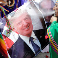 Peruvian shamans hold a poster of U.S. President Donald Trump as they perform a ritual of predictions for the new year at Pescadores beach in   Lima on Thursday. | REUTERS