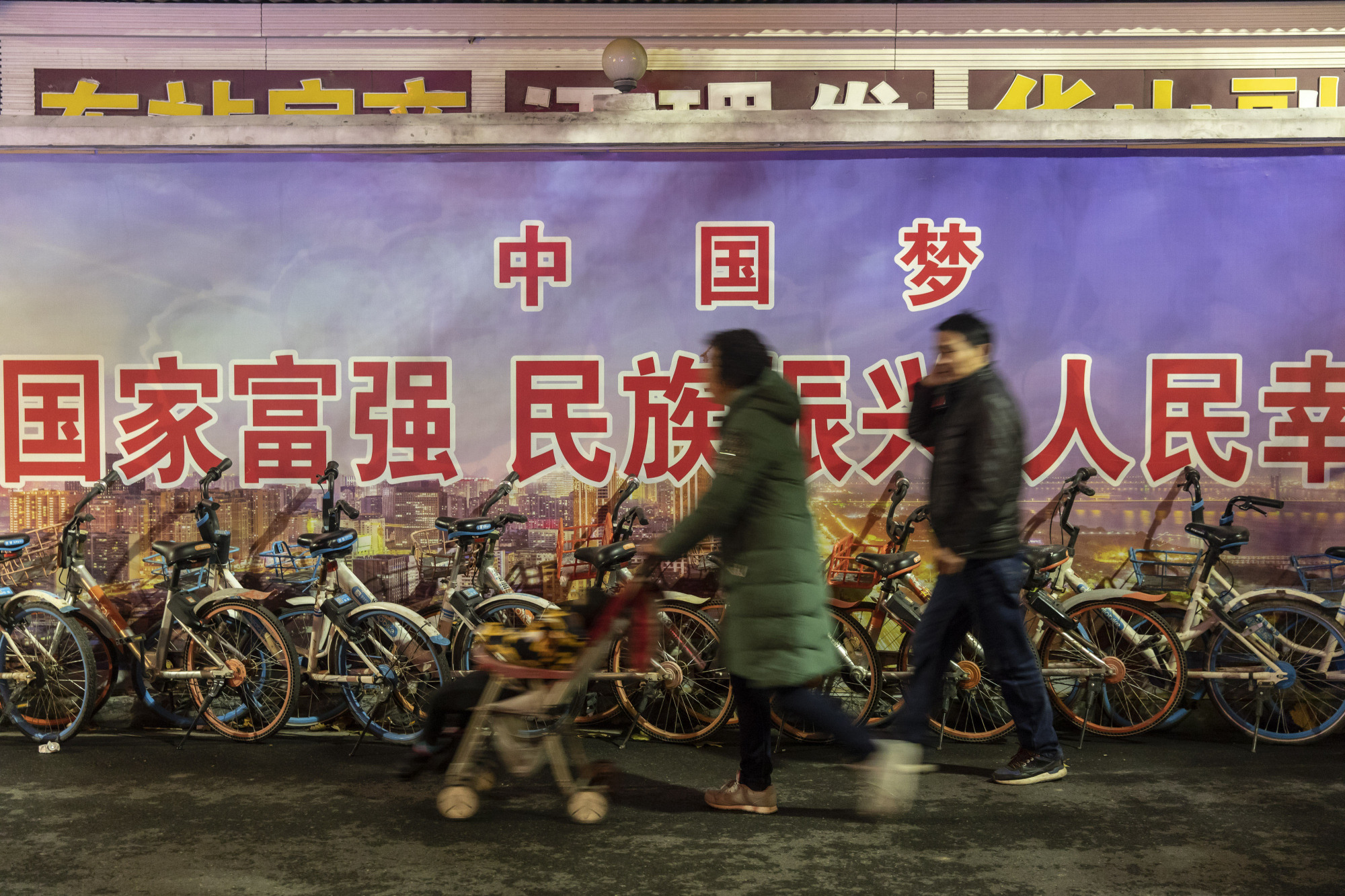 Pedestrians in walk past a government mural referencing the 'Chinese Dream' in the city of Wuhan, Hubei province, on Dec. 9. | BLOOMBERG