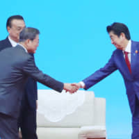 Prime Minister Shinzo Abe shakes hands with South Korean President Moon Jae-in as Chinese Premier Li Keqiang looks on at the 8th trilateral leaders\' summit between China, South Korea and Japan in Chengdu, China on Dec. 24. Managing ties with China and South Korea are among the foreign policy challenges that Abe will face in 2020. | REUTERS