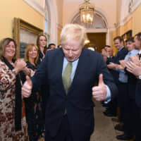 British Prime Minister Boris Johnson is greeted by staff as he arrives back at 10 Downing Street in central London on Friday  following an audience with the queen. | AFP-JIJI
