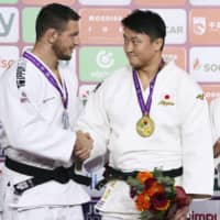 Heavyweight champion Hisayoshi Harasawa (right) shakes hands with Lukas Krpalek of the Czech Republic on Saturday at the World Judo Masters in Qingdao, China. Krpalek pulled out of the final with a sore back. | KYODO